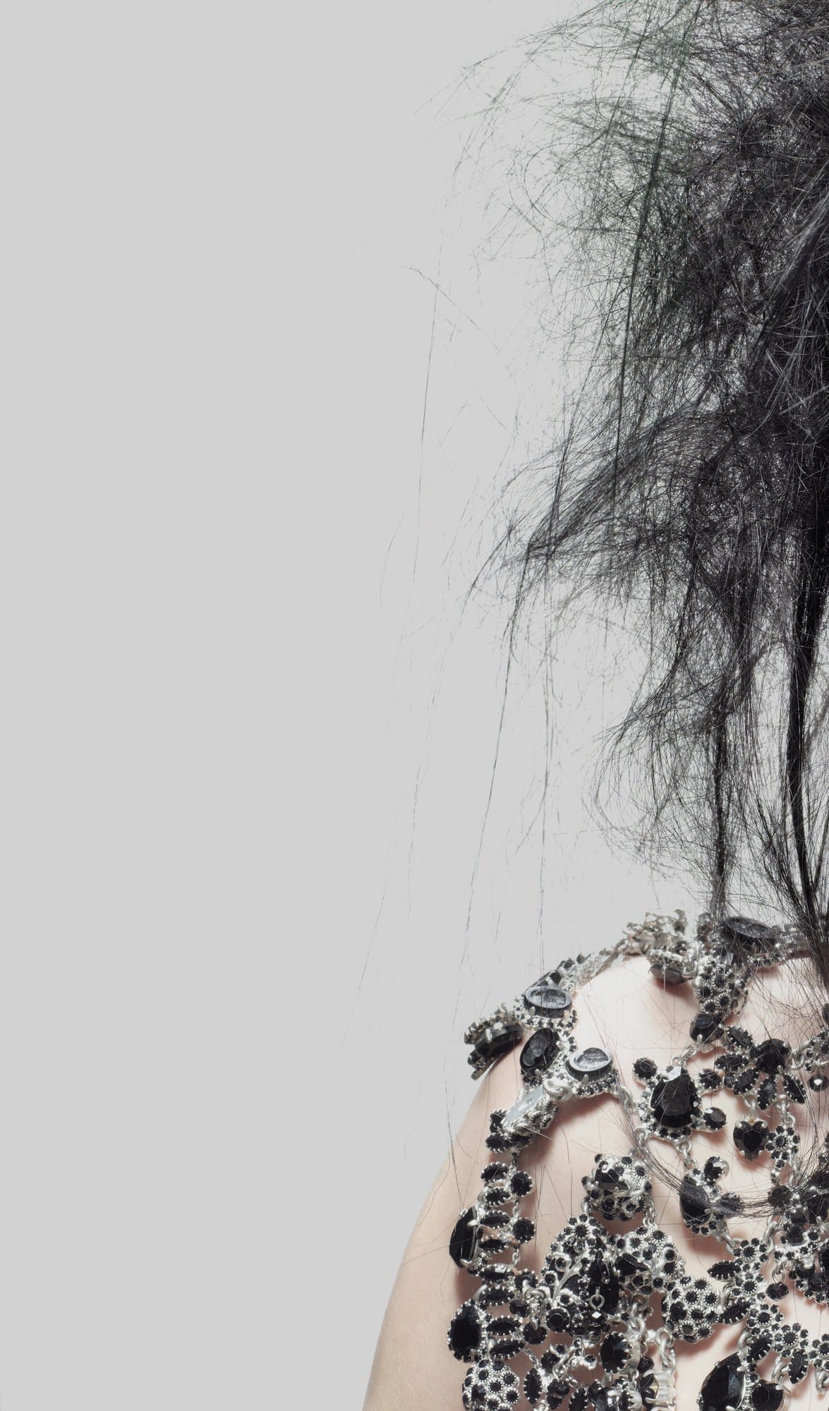 Close-up of tousled dark hair over a bare shoulder with black jewelled embellishment – TIGI Collections, Anthony Mascolo 2007